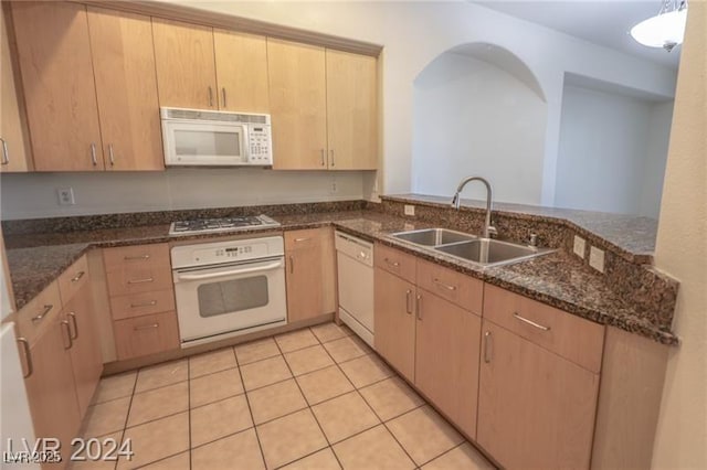 kitchen featuring light tile patterned flooring, white appliances, sink, and light brown cabinetry