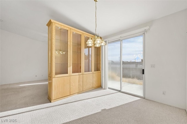 carpeted spare room with an inviting chandelier