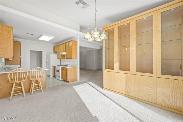 kitchen with a notable chandelier, decorative light fixtures, white appliances, light carpet, and a breakfast bar