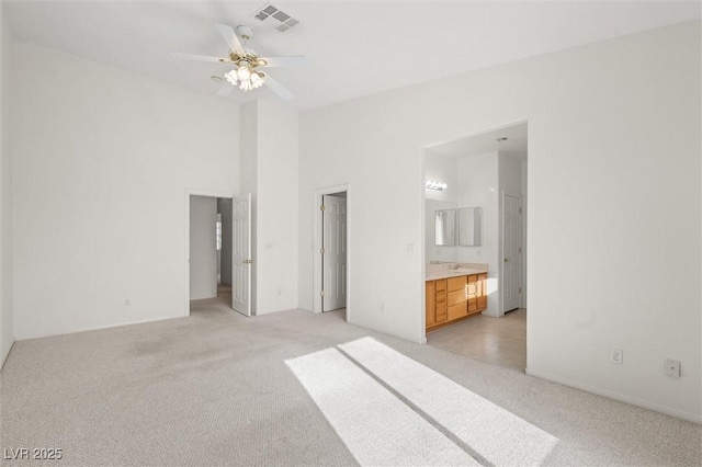 empty room featuring ceiling fan, light carpet, and a high ceiling