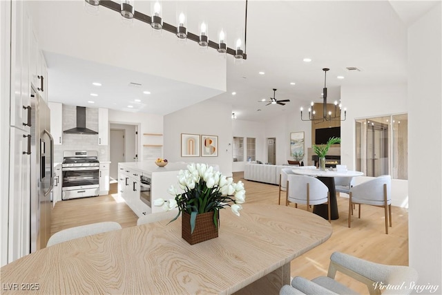 dining space featuring ceiling fan, light wood-type flooring, and high vaulted ceiling