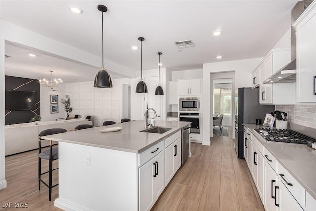 kitchen featuring a center island with sink, white cabinetry, sink, and stainless steel appliances