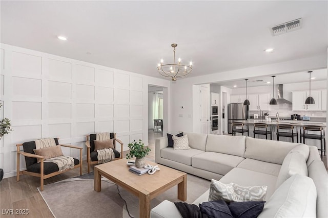 living room with light hardwood / wood-style floors, sink, and a chandelier