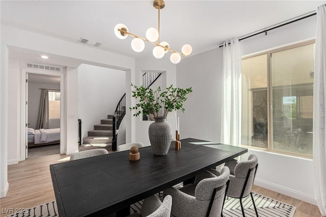 dining space with plenty of natural light, light hardwood / wood-style floors, and a chandelier