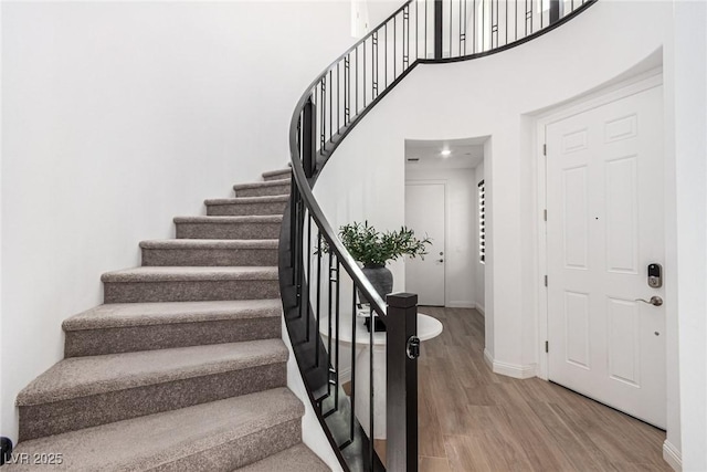 staircase featuring a towering ceiling and wood-type flooring