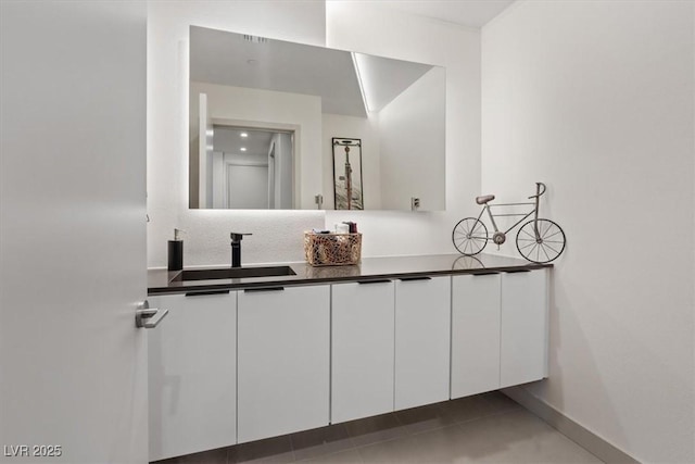 bathroom featuring double vanity, baseboards, and a sink