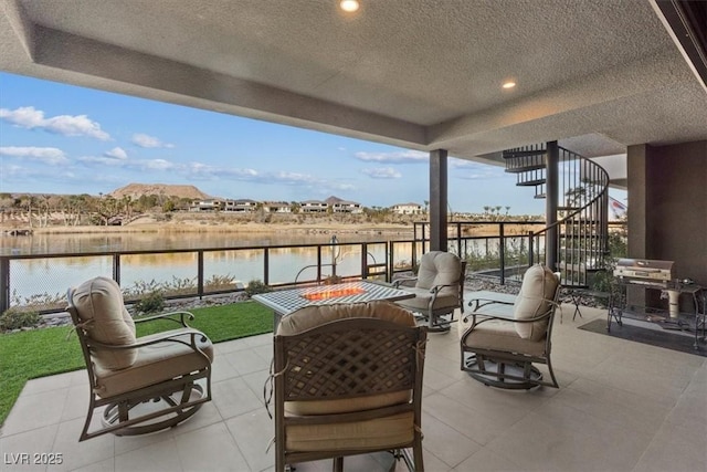 view of patio with a water view, fence, and stairway