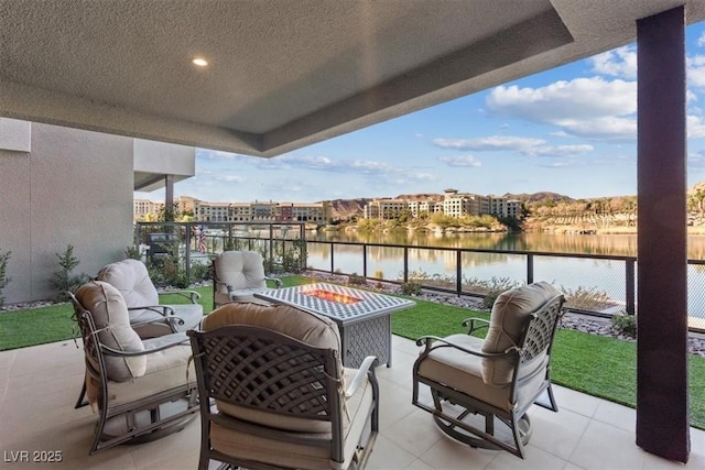 balcony with an outdoor living space with a fire pit, a water view, and a patio