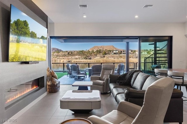 living room with recessed lighting, visible vents, and a glass covered fireplace