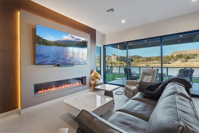 living area featuring recessed lighting, baseboards, visible vents, and a glass covered fireplace