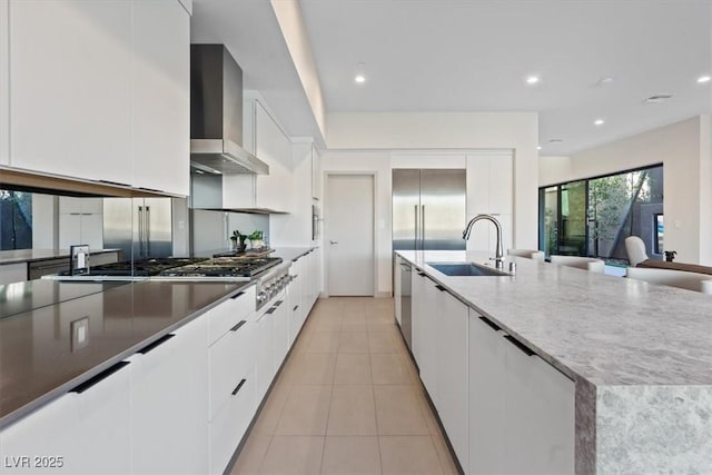 kitchen featuring stainless steel appliances, white cabinetry, a sink, modern cabinets, and wall chimney exhaust hood