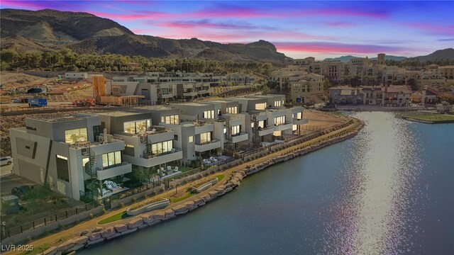 aerial view at dusk featuring a water and mountain view