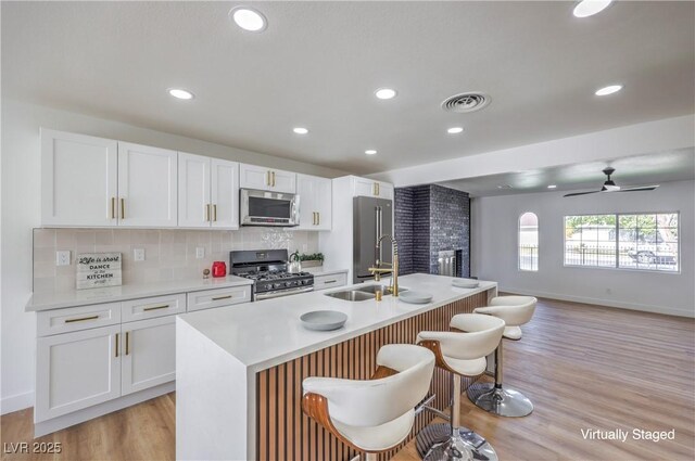 kitchen featuring appliances with stainless steel finishes, white cabinetry, and a kitchen island with sink