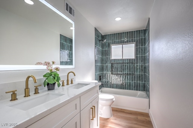 full bathroom with toilet, vanity, wood-type flooring, and tiled shower / bath