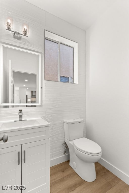 bathroom featuring vanity, wood-type flooring, tile walls, and toilet