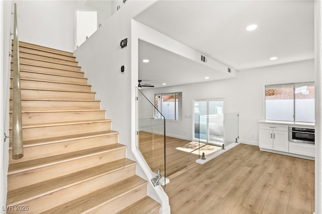 stairs featuring ceiling fan and hardwood / wood-style floors