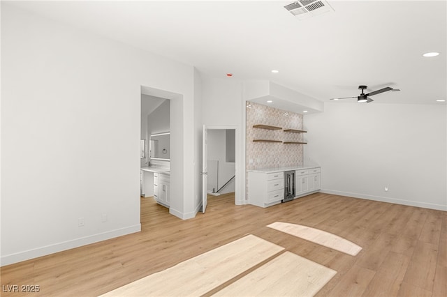 unfurnished living room featuring ceiling fan, light wood-type flooring, and beverage cooler