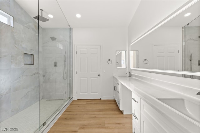 bathroom with a tile shower, vanity, and hardwood / wood-style flooring