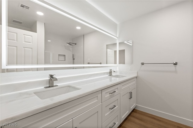 bathroom with hardwood / wood-style floors, vanity, and a shower