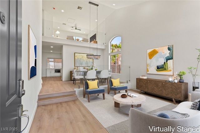 living room featuring light hardwood / wood-style floors, high vaulted ceiling, and ceiling fan