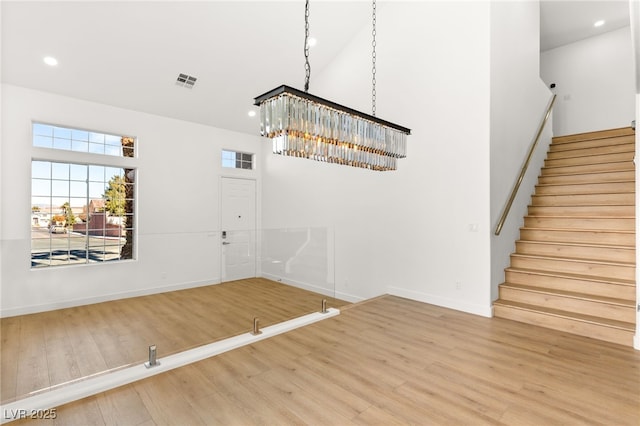 foyer with wood-type flooring, a towering ceiling, and a chandelier