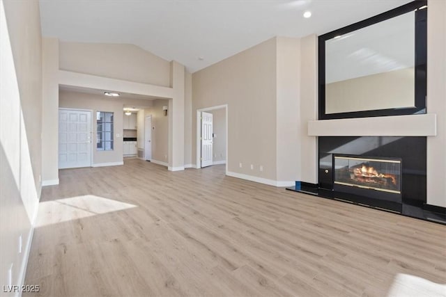 unfurnished living room with light wood-type flooring and lofted ceiling