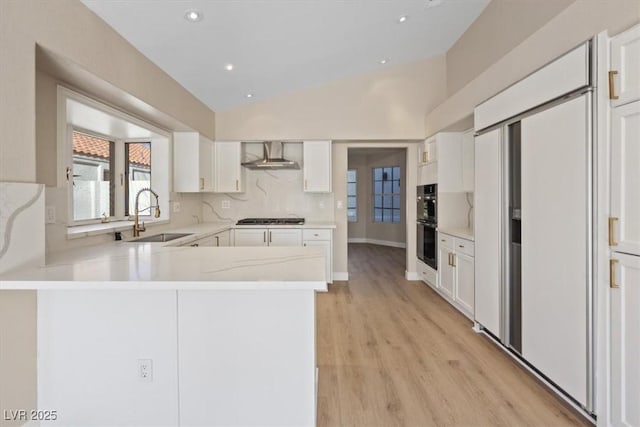 kitchen with white cabinetry, kitchen peninsula, sink, and vaulted ceiling