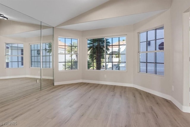 empty room with light hardwood / wood-style floors and lofted ceiling