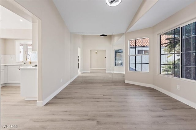 corridor with sink, vaulted ceiling, and light hardwood / wood-style flooring