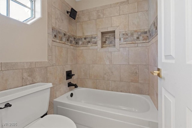 bathroom with tiled shower / bath, tile walls, and toilet