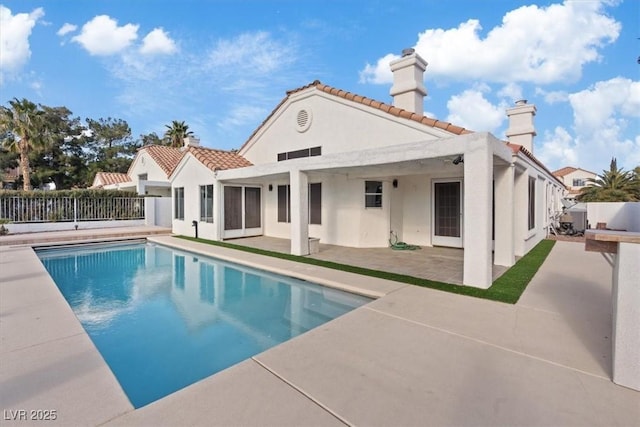 rear view of house with a fenced in pool and a patio area