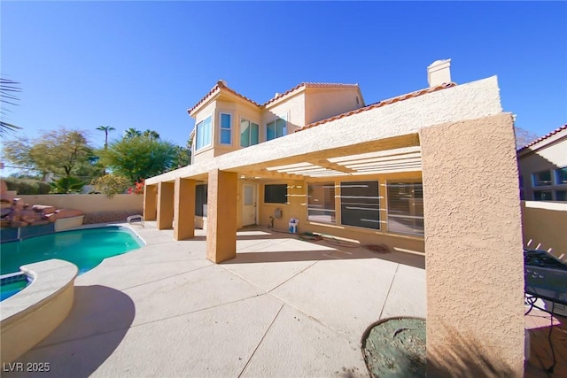 rear view of property with a fenced in pool and a patio area