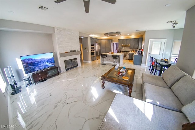 living room featuring a fireplace and ceiling fan