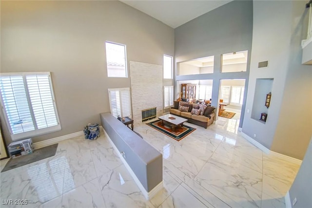 living room with plenty of natural light, a towering ceiling, and a fireplace