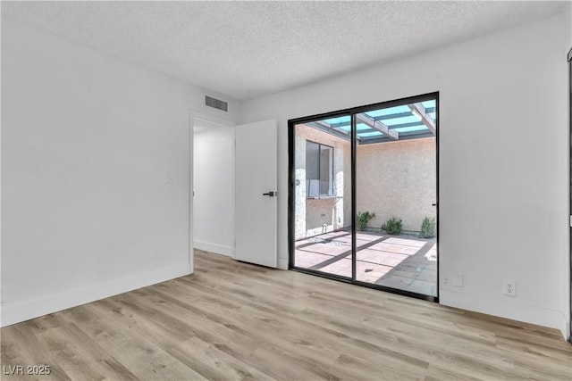 empty room featuring light hardwood / wood-style flooring and a textured ceiling