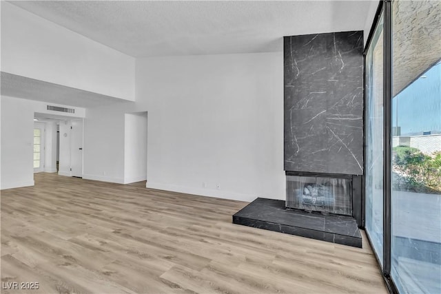 unfurnished living room with plenty of natural light, a premium fireplace, and light hardwood / wood-style flooring