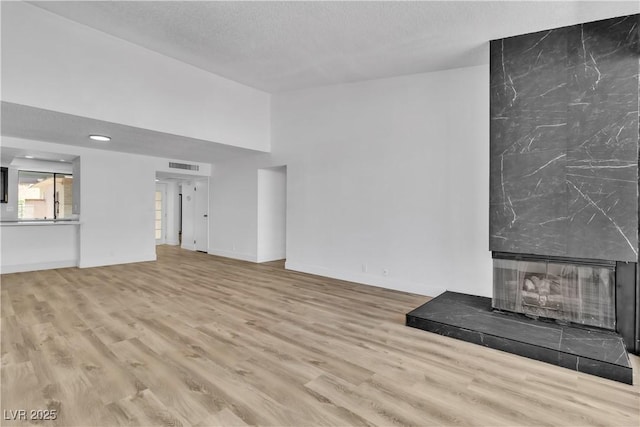 unfurnished living room featuring a textured ceiling, light hardwood / wood-style floors, and a fireplace