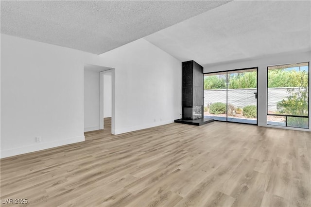 unfurnished living room featuring light wood-type flooring, a textured ceiling, and lofted ceiling