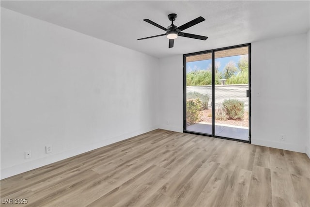 empty room with ceiling fan, floor to ceiling windows, and light hardwood / wood-style flooring