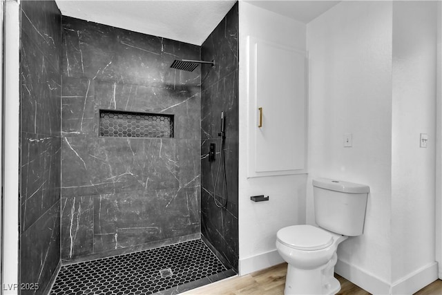 bathroom with a tile shower, hardwood / wood-style flooring, and toilet