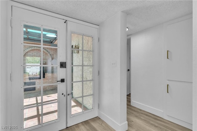 entryway featuring french doors, a textured ceiling, and light hardwood / wood-style flooring