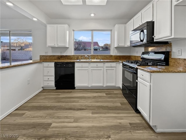 kitchen with white cabinets, light wood-type flooring, sink, and black appliances