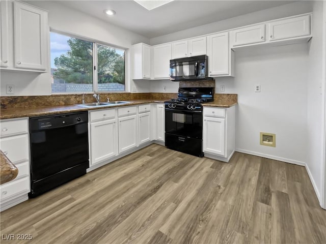 kitchen featuring sink, white cabinets, black appliances, and light hardwood / wood-style floors