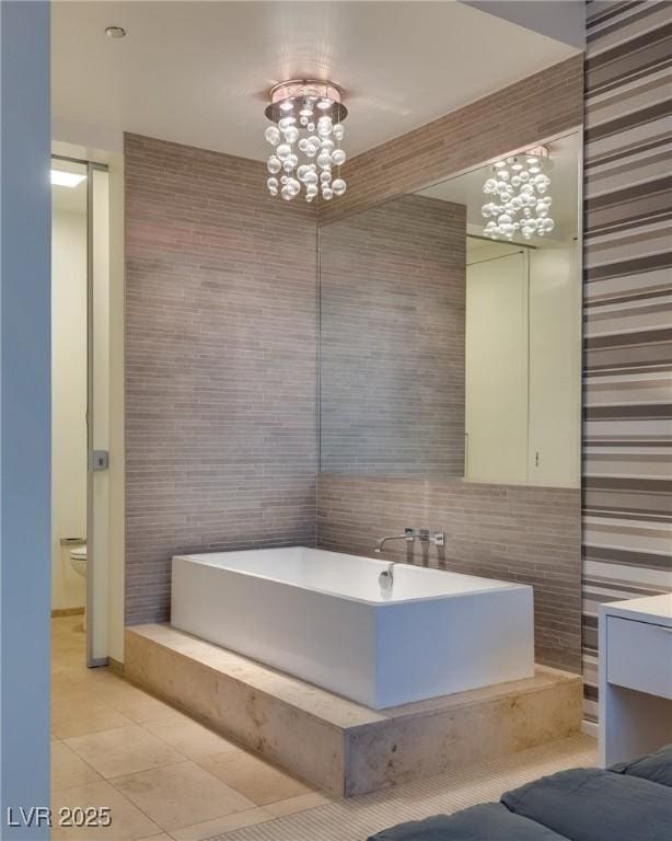 bathroom with tile walls, a chandelier, tile patterned flooring, vanity, and toilet