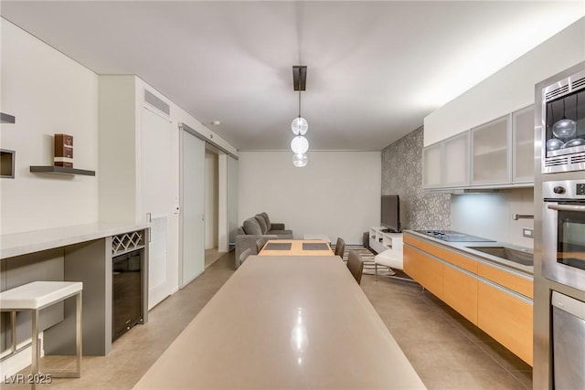 kitchen with sink, hanging light fixtures, backsplash, black electric stovetop, and stainless steel oven