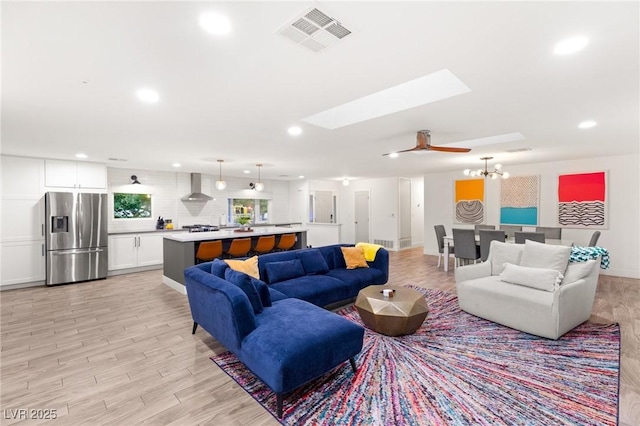 living room featuring light hardwood / wood-style flooring and ceiling fan with notable chandelier