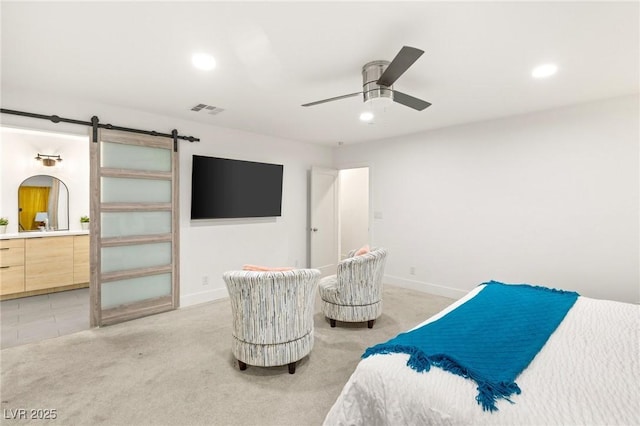 carpeted bedroom featuring a barn door, ceiling fan, and ensuite bathroom