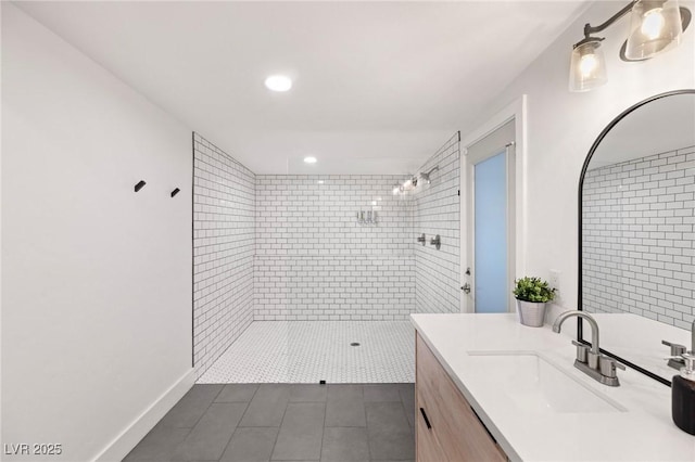 bathroom with a tile shower, vanity, and tile patterned floors