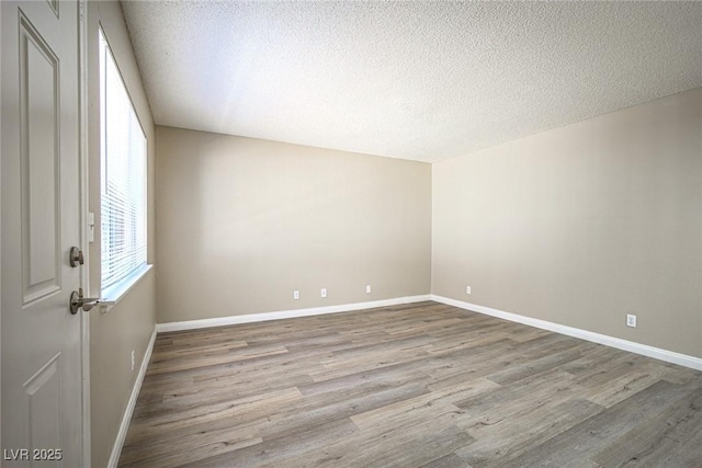 unfurnished room featuring a wealth of natural light, light hardwood / wood-style flooring, and a textured ceiling