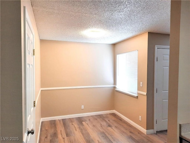 unfurnished room with a textured ceiling and light hardwood / wood-style floors